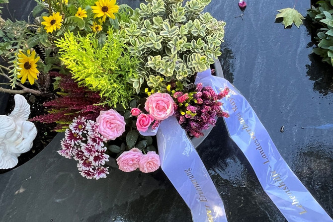 Zu sehen ist das Grab mit Blumenschmuck.
